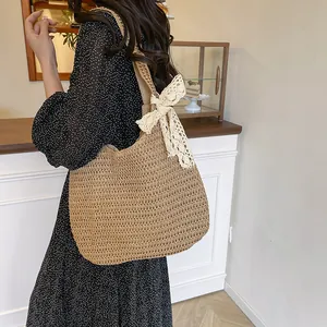 Sac à bandoulière en paille tressé avec grand nœud en dentelle dans un décor de café