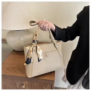 Detail of minimalist beige tote bag with a decorative baroque silk scarf handle