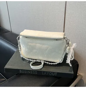 Detail of white faux snakeskin box bag with silver chain and pearl lace charm