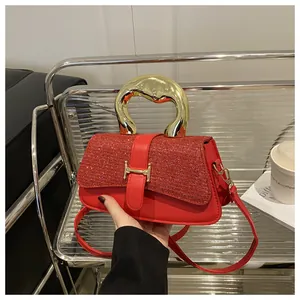 Detail of red handbag with glitter flap, large gold curved handle and H-shaped buckle