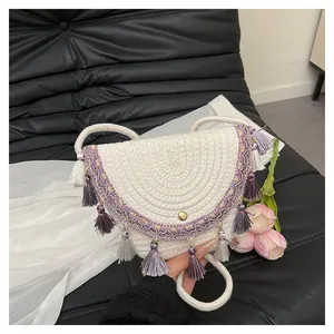 Détail du sac selle tissé avec pompons violets et fermoir magnétique doré