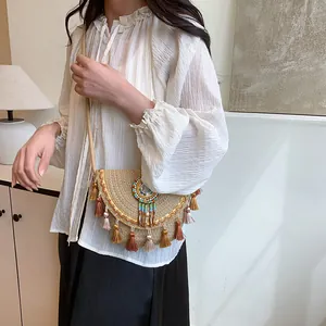 Sacoche bohème en paille avec pompons colorés et perles porté par un modèle