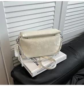 Detail of off-white faux snake skin box bag featuring lace trim and pearl fringe pendant