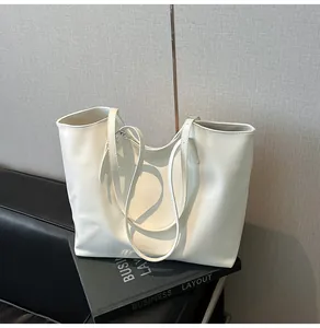 Borsa tote minimalista in pelle bianca su scrivania con disposizione aziendale