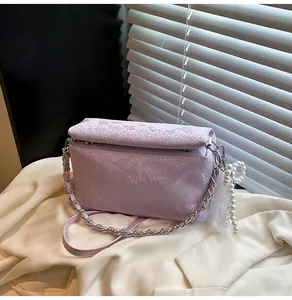 Detailed texture of lavender snake-embossed box bag with lace and pearl charm