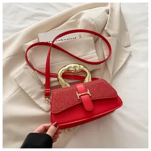 Close-up of red leather handbag with sequin flap and gold H-shaped buckle detail