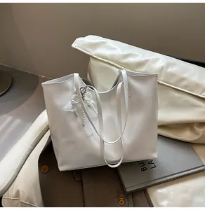 Dettaglio della borsa tote in pelle PU bianca con fiocco di pizzo e ciondolo