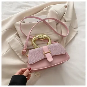 Detail of pink crossbody bag with gold H-buckle and textured fabric flap on blazer