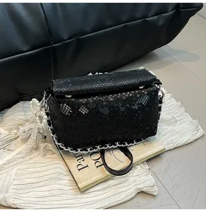 Detail of black snake-pattern box bag with silver chain, pearl and lace charms
