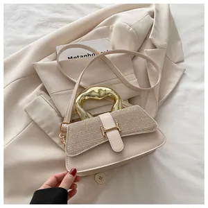 Detail view of beige crossbody bag with gold glitter lid and unique metal handle