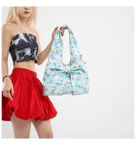 Detail der hellblauen floralen Handtasche mit großer Schleife und weißen Stickereien