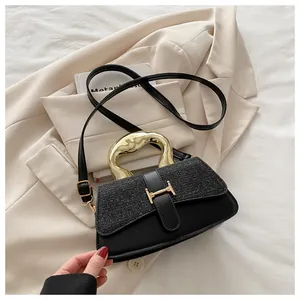 Detail of elegant black crossbody bag with gold hardware and sparkling sequin flap texture