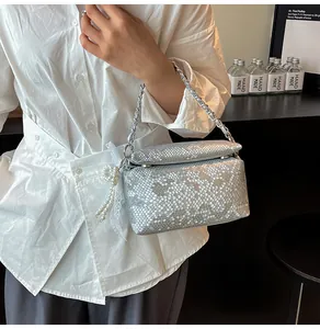 Detail of silver snake pattern box bag with metal chain strap and pearl lace charm