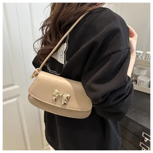 Détail du sac à bandoulière beige élégant avec fermoir nœud doré et cuir PU lisse