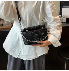 Detail of black faux snake leather handbag with silver chain and crossbody strap