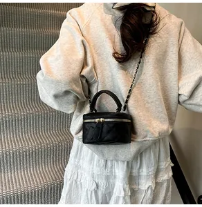 Quilted mini vanity bag with chain strap shown on model against a stone step background