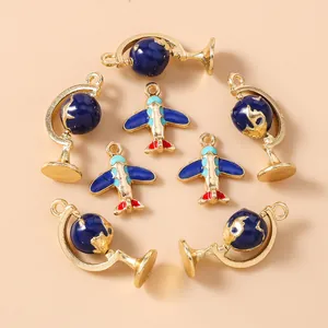 Close-up of gold-plated airplane and globe enamel charms for DIY jewelry making