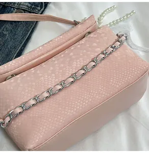 Detailed macro view of pink PU leather with snake skin texture and metal chain strap