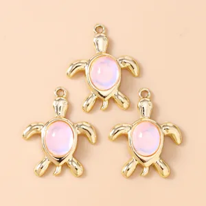Three golden turtle pendants with pink cat eye stone inlays for DIY jewelry making