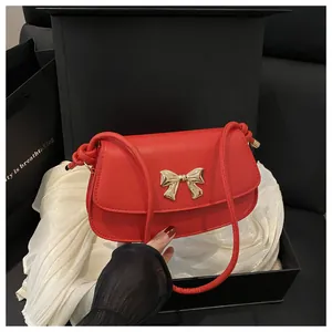 Vue détaillée du sac bandoulière rouge avec nœud doré dans une boîte cadeau