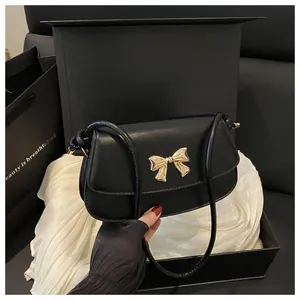 Vue détaillée du sac bandoulière noir avec nœud doré et son coffret cadeau élégant