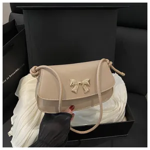 Détail du sac beige avec boucle noeud doré dans un coffret cadeau élégant