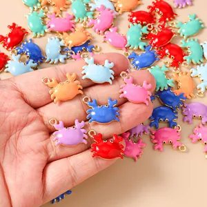 Detail showing colorful enamel crab charms for DIY jewelry making held in hand