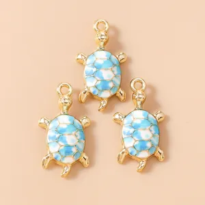 Macro shot of three golden sea turtle charms with blue and white enamel for DIY jewelry