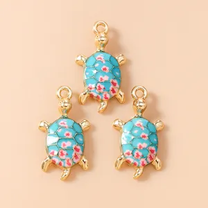 Macro view of blue enamel sea turtle charms with floral patterns and gold metal edges