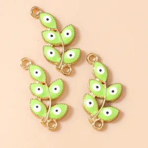 Detail of green leaf connectors with evil eye charms in gold finish for DIY jewelry