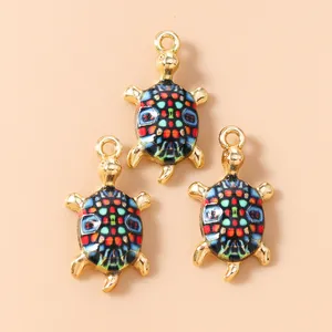 Detailed close-up of colorful enamel turtle pendants with gold frames and DIY hanging loops