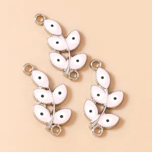 Detail of leaf-shaped charms with pink enamel and evil eye motif for DIY jewelry