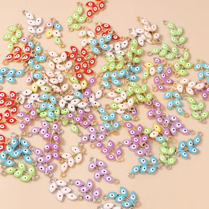 Flat lay of colorful enamel evil eye leaf pendants with metal rings for jewelry DIY