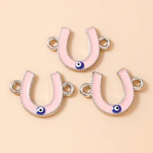 Macro detail of three pink enamel horseshoe charms with evil eye motifs for jewelry DIY