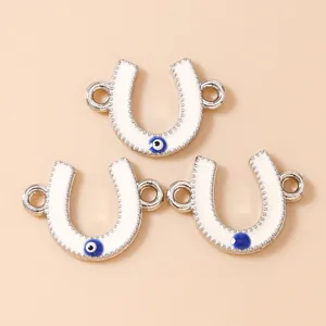 Macro shot of horseshoe-shaped white enamel charms with evil eye detail and connectors
