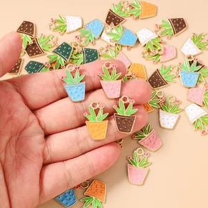 Detailed view of colorful enamel cactus pot pendants held in hand for DIY jewelry making