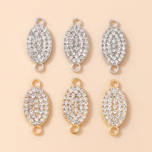 Close-up of gold and silver oval connector pendants with tiny rhinestones for DIY jewelry
