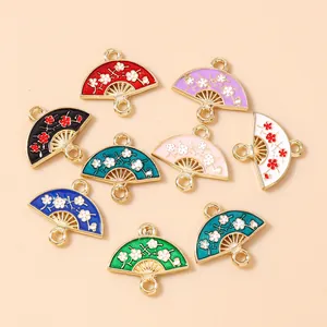 Flat lay of eight colorful enamel fan charms with flower patterns for DIY jewelry making