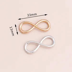 Detalle macro de dijes de símbolo infinito 33x13mm en aleación pulida de oro y plata
