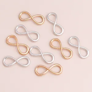 Detalle de dijes de aleación con símbolo de infinito en oro y plata para bisutería DIY
