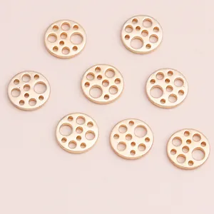 Set of 8 golden hollow geometric round charms for jewelry making on pink background