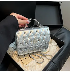Détail d'un sac argenté matelassé avec étoile en strass et chaîne dans une boîte cadeau
