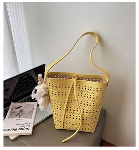 Detail view of yellow hollow-out bucket bag with laser-cut patterns and plush puppy charm