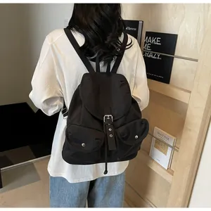 Vue arrière du modèle portant un sac à dos en nylon noir avec rabat et doubles poches
