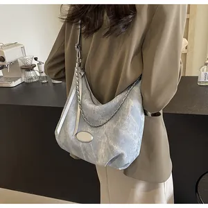 Detail view of light blue hobo bag with textured finish and silver chain accessory