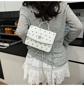 Vue détaillée d'un sac bandoulière blanc matelassé avec des clous en étoile argentés