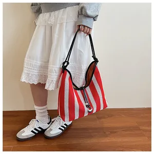 Detail of red and white striped mesh tote bag with black leather handles and metal ring charms