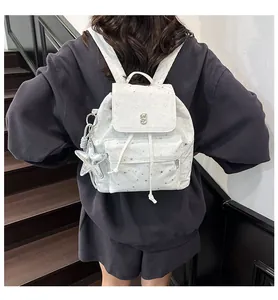 Detail eines Rucksacks mit silbernem Sternmuster, J-Logo aus Metall und Sternanhänger