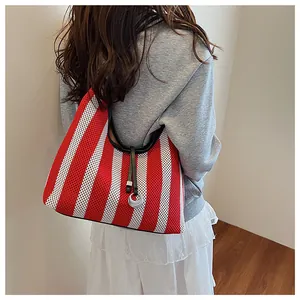 Detail of red and white striped knit tote bag with silver ring charm and black strap