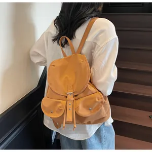 Détail d'un sac à dos en toile ocre avec fermeture à cordon et deux poches avant à rabat